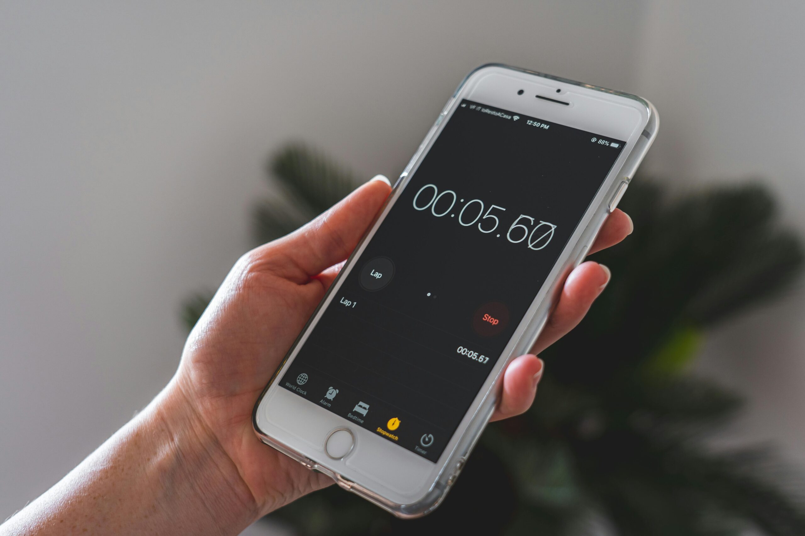 Close-up of a hand holding a smartphone with a stopwatch app running.